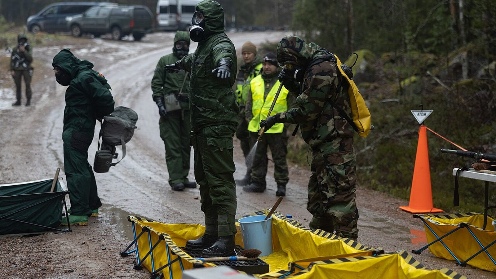 A decontamination line set up outdoors, with responders in protective suits working through it